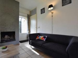 uma sala de estar com um sofá preto e uma lareira em Appealing Holiday Home in Guelders near Forest em Lochem
