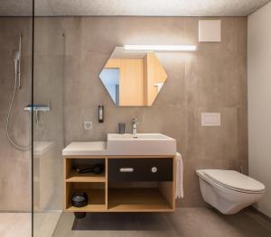 a bathroom with a sink and a toilet and a mirror at The Lab Hotel & Apartments in Thun