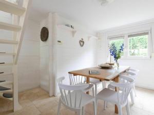 une salle à manger avec une table en bois et des chaises blanches dans l'établissement Cozy house with sauna in Oostkapelle with forest, à Oostkapelle
