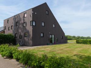 ein schwarzes Gebäude mit einem Rasenplatz davor in der Unterkunft Luxury holiday home with private terrace in Langweer