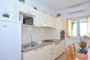 una cocina con armarios blancos y fregadero en Apartments Punta Milna, en Hvar