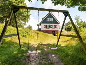 a swing set in front of a house at Beautiful dune villa with thatched roof on Ameland in Buren