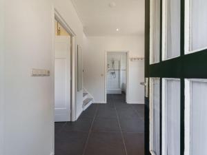 a hallway with white walls and a tiled floor at Beautiful dune villa with thatched roof on Ameland in Buren