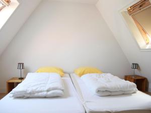 HippolytushoefにあるComfy villa in Wieringer style near the Wadden Seaのベッドルーム1室(白いシーツと黄色い枕のベッド2台付)