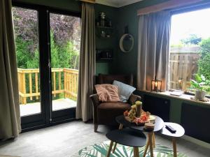 uma sala de estar com uma cadeira e uma mesa em Tasteful chalet with veranda in the Veluwe em Garderen