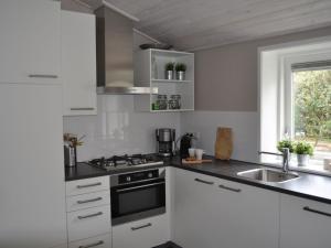 a kitchen with white cabinets and a sink at bungalow situated directly at a large sand dunes in Ballum