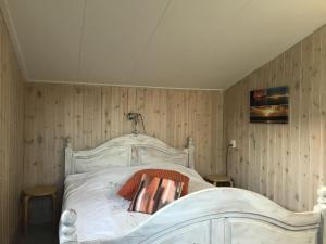 een wit bed in een kamer met houten wanden bij Secluded Holiday Home in Ballum Frisian Islands in Ballum