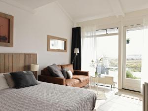 um quarto com uma cama e um sofá em Modern suites near beach em Callantsoog
