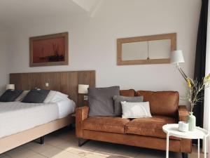 1 dormitorio con sofá, cama y mesa en Modern suites near beach, en Callantsoog