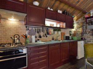 a kitchen with wooden cabinets and a stove top oven at Cozy holiday home with a hot tub in Musselkanaal
