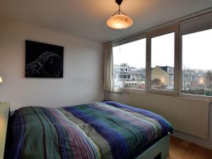 a bedroom with a bed and a large window at Terrace Apartment with Lush Garden in Voorburg