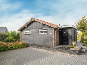 a small house with a black door on a patio at Attractive holiday home with large terrace in Kattendijke