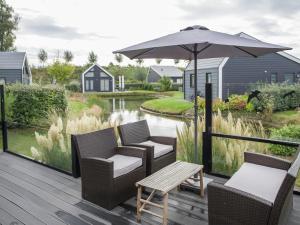 a deck with chairs and an umbrella and a table at Attractive holiday home with large terrace in Kattendijke