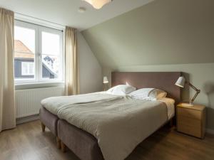 een slaapkamer met een groot bed en een raam bij Luxurious villa a 5 minute walk from beach in Cadzand