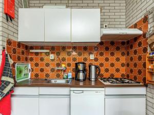 una cocina con armarios blancos y azulejos de color naranja en Comfortable detached bungalow 65 m2, en Kamperland