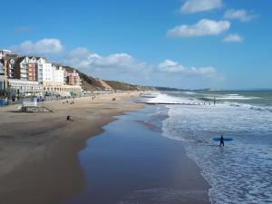 a person walking on the beach with a surfboard at The Westby in Bournemouth