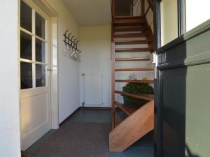 un pasillo con una escalera de madera junto a una puerta en Linked farm in Elsendorp with a recreation barn, en Elsendorp