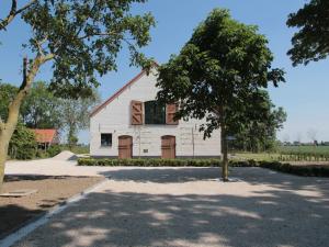 une grange blanche avec un arbre devant elle dans l'établissement Elegant Farmhouse in Zuidzande with Private Garden, à Zuidzande