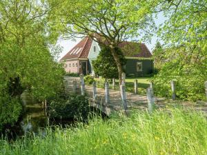 uma casa verde e uma cerca em frente a uma casa em Spacious farmhouse in wooded area em Zuidoostbeemster