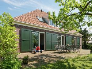 uma casa com portas verdes de garagem e uma mesa e cadeiras em Spacious farmhouse in wooded area em Zuidoostbeemster