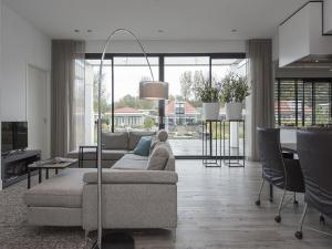 a living room with a couch and a table with chairs at Luxury villa with private jetty in quiet park in Zeewolde