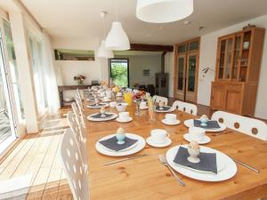 een lange tafel met stoelen, borden en kommen erop bij Luxurious Mansion in Callantsoog with Sauna in Julianadorp