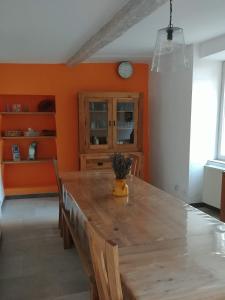 une salle à manger avec une grande table en bois et des murs orange dans l'établissement Gîte Pilpoil, à Sault