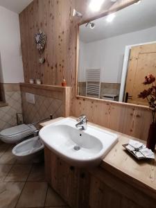 bagno con lavandino, servizi igienici e specchio di Taverna Larice a Valdidentro