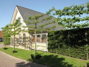 een wit huis met een heg ervoor bij Attractive detached holiday home in small scale holiday park in Schoorl