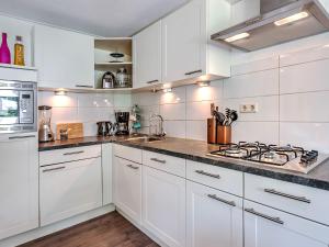 a white kitchen with white cabinets and a stove at Restful Holiday Home with a Private Terrace and hottub in Veendam