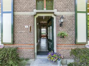 een bakstenen gebouw met een groene deur en bloemen bij Holiday home in the central location in Terneuzen
