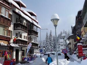 Una calle cubierta de nieve con gente caminando por ella en Pensiunea Pasul Clabucetului, en Predeal