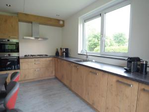 a kitchen with wooden cabinets and a large window at Luxury Villa in Texel with Private Garden in Westermient