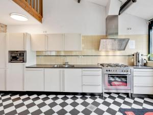 een keuken met witte apparatuur en een geruite vloer bij Spacious farmhouse in Limburg near forest in Sint Antoniusbank