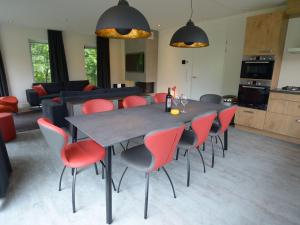 a dining room with a table and red chairs at Luxury Villa in Texel with Private Garden in Westermient