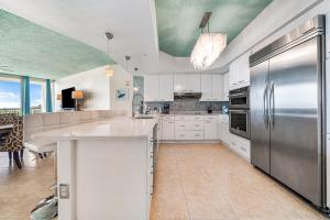 uma cozinha com armários brancos e um frigorífico de aço inoxidável em Newly Updated Caribe 213B em Orange Beach