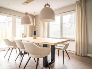 a dining room with a wooden table and white chairs at Modern Holiday Home in De Cocksdorp in De Cocksdorp