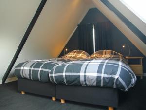 een slaapkamer met een bed met een gestreept dekbed bij Holiday home for two people at a peaceful in Heiloo