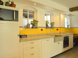 Eine Küche mit weißen Schränken und gelben Fliesen in der Unterkunft Holiday Home in Haaren near De Efteling in Haaren