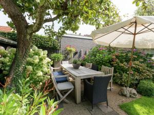 a table and chairs with an umbrella in a garden at Apartment in Bergen near Sandy Beaches in Bergen