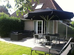 een patio met een tafel en stoelen en een parasol bij Lush holiday home in Earnew ld in Earnewâld