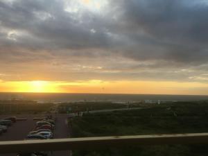 ノールトウェイクにあるCosy apartment in Noordwijk aan Zee with balconyの夕日の前に車を駐車した駐車場