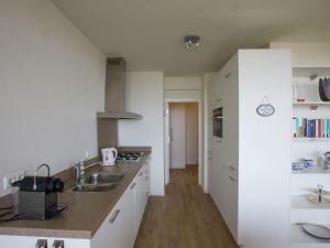 ノールトウェイクにあるCosy apartment in Noordwijk aan Zee with balconyの白いキャビネットとシンク付きのキッチン