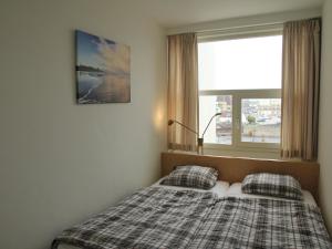 ノールトウェイクにあるCosy apartment in Noordwijk aan Zee with balconyの窓付きのベッドルームに枕2つ付きのベッド1台が備わります。