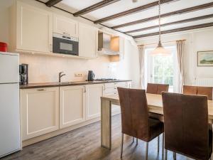 a kitchen with white cabinets and a table and chairs at Great Farmhouse in De Cocksdorp with Garden in De Cocksdorp