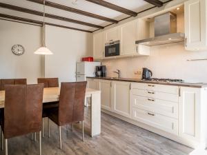 une cuisine avec des placards blancs et une table et des chaises en bois dans l'établissement Great Farmhouse in De Cocksdorp with Garden, à De Cocksdorp