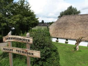 萊爾丹的住宿－Quaint Farmhouse near River in Oosterwijk，茅草屋顶建筑前的街道标志