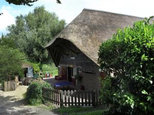 萊爾丹的住宿－Quaint Farmhouse near River in Oosterwijk，一座带茅草屋顶的小房子,设有围栏