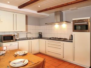 a kitchen with white cabinets and a wooden table at Quaint Farmhouse near River in Oosterwijk in Leerdam