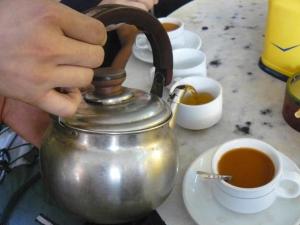 una persona che tiene in mano un bollitore per il tè e una tazza di caffè di 4321 B&B Stazione Trastevere a Roma